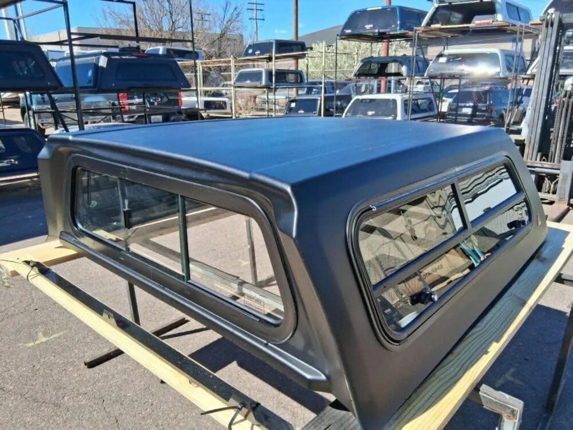 Toyota Tacoma truck topper installed on pickup bed, Toyota Tacoma camper shell truck bed topper, Toyota Tacoma fiberglass truck cap, Toyota Tacoma aluminum truck topper, Toyota Tacoma high-rise camper shell, Toyota Tacoma soft truck bed topper, Toyota Tacoma overland truck cap, Toyota Tacoma commercial truck bed topper, Toyota Tacoma camper shell with side windows, Toyota Tacoma truck topper for 5-foot bed, Toyota Tacoma truck topper for 6-foot bed, Black Toyota Tacoma truck cap installed on pickup,